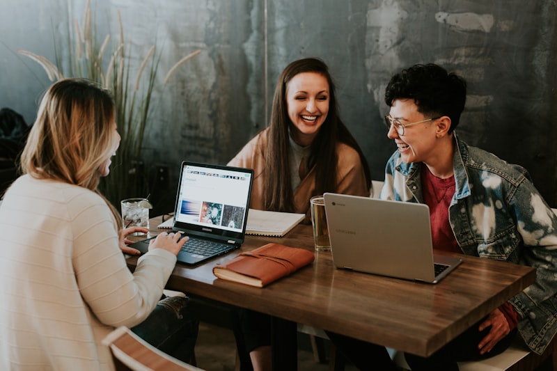 Three people working together at a table with laptops — suggested image — client to supply the final photograph