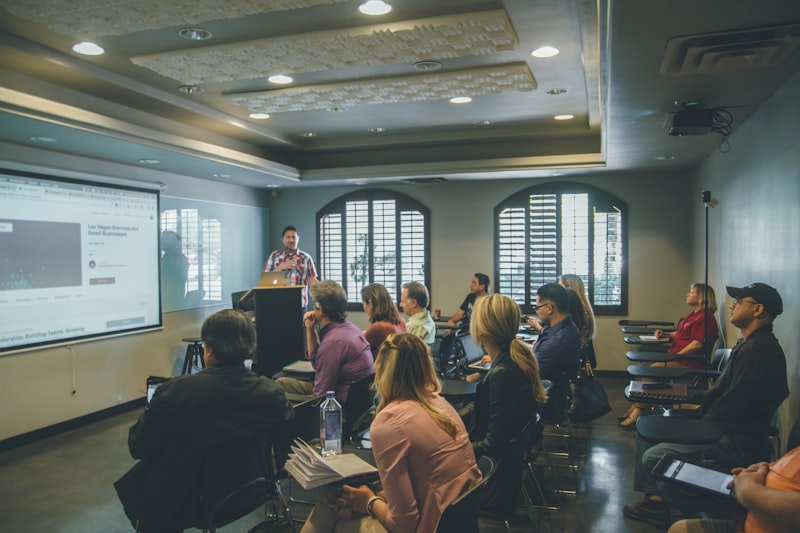 A lecture room with an audience seated facing a presentation screen — suggested image — client to supply the final photograph